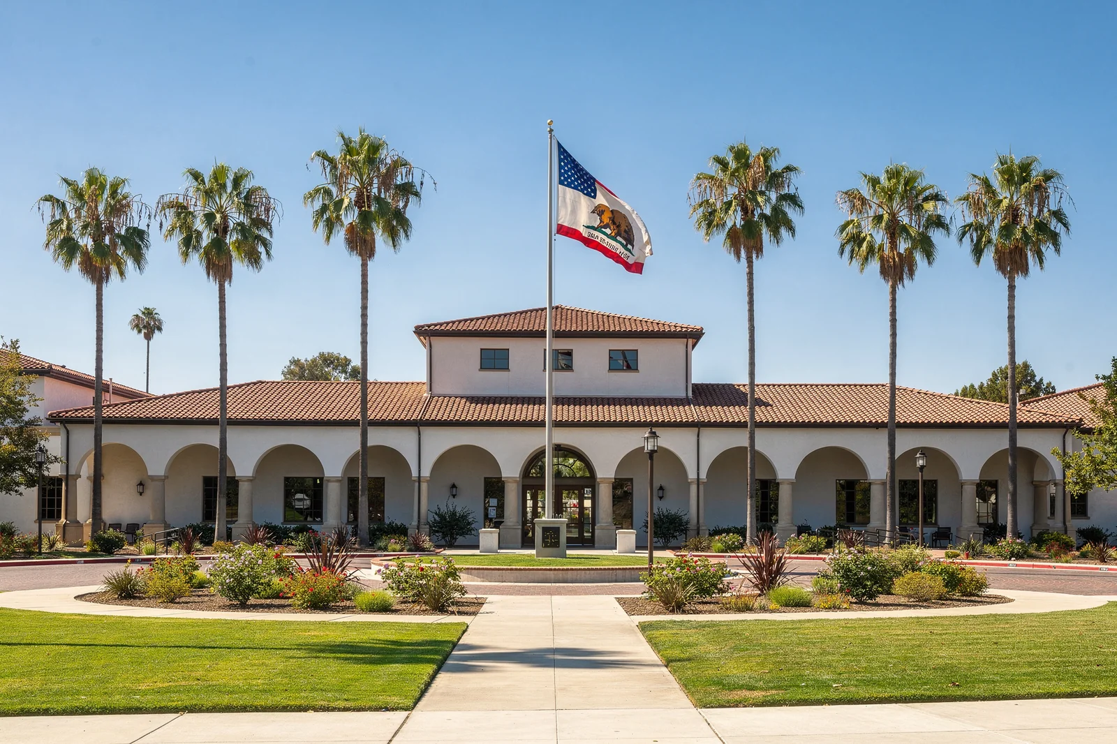 California K-12 public school building with palm trees and American and California state flags